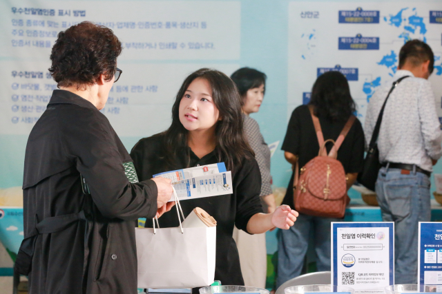 천일염이력제 홍보관을 찾은 관람객이 ‘국가별 천일염 비교’ 코너에서 국산 천일염의 특징과 이력 확인 방법에 대한 설명을 듣고 있다