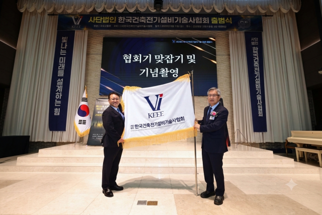 한국건축전기설비기술사협회 김동진 초대 이사장(왼쪽)이 협회기를 맞잡고 있다