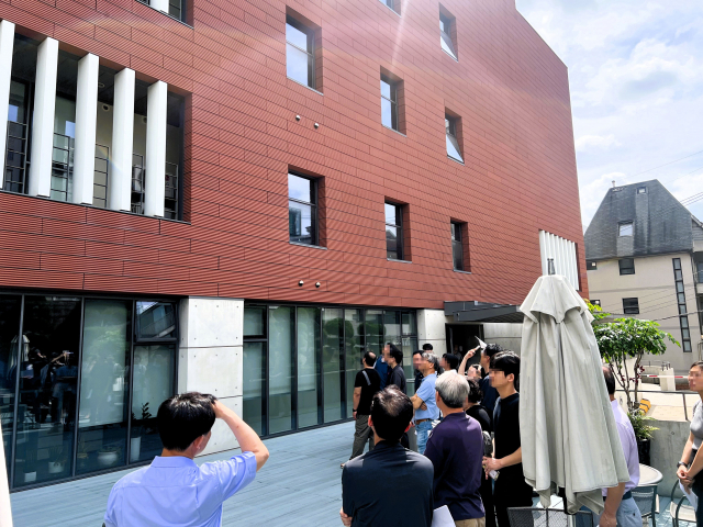 엔알비 임직원들이 홍찬기 건축가의 현장 설명을 들으며 새롬빌딩의 외장과 입면 구성을 살펴보고 있다