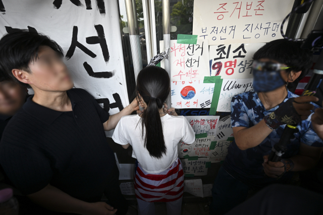 6·3 지방선거 투표용지 부족 사태로 시작한 서울 송파구 올림픽공원 핸드볼경기장 일대 '개표소 봉쇄 시위'가 이어지는 가운데 16일 한 시위 참가자가 대한체육회 등 입주 단체 관계자들의 진입을 막아서고 있다. 연합뉴
